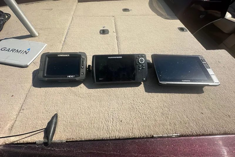 Slide: The Image of Three marine GPS devices on a boat deck, including Lowrance, Humminbird, and Garmin models. - 11