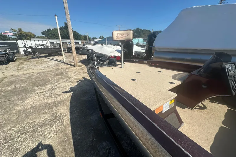 Slide: The Image of 1998 Charger 186 VF boat in outdoor storage, featuring a spacious deck and covered seating. - 12