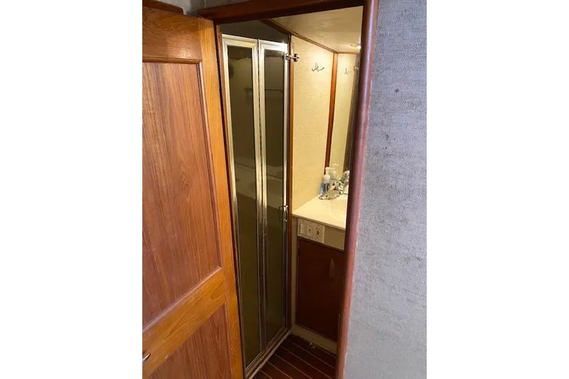 Slide: The Image of Interior of 1988 Buddy Davis 47 Custom Carolina yacht, featuring a compact bathroom with wooden accents. - 21
