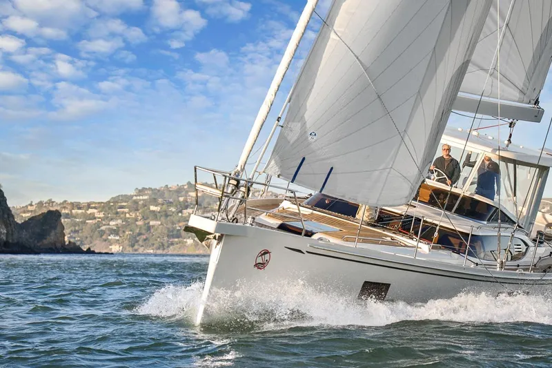 Slide: The Image of 2020 Hylas H57 yacht sailing on open water with scenic coastal backdrop. - 5