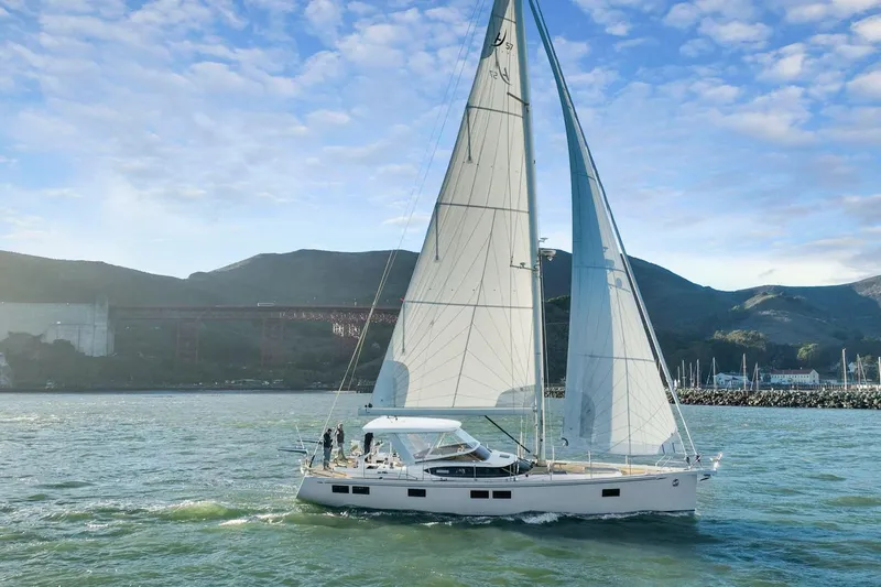 Slide: The Image of 2020 Hylas H57 sailboat cruising near a scenic coastline under a clear blue sky. - 12