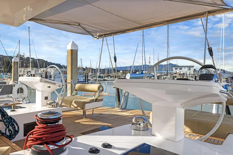 Slide: The Image of Luxury Hylas H57 yacht cockpit with dual steering wheels, docked in a scenic marina, 2020 model. - 56