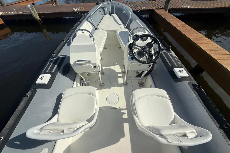 Slide: The Image of 2012 Zodiac Bayrunner Pro 650 boat interior with white seating and steering wheel, docked at marina. - 11