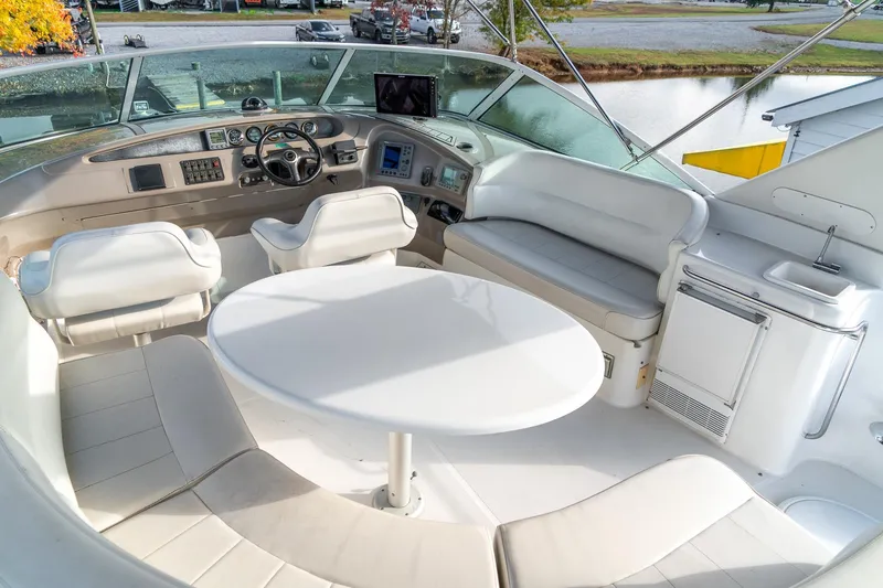 Slide: The Image of 2000 Carver 450 Voyager Pilothouse interior with helm, seating, and table on a sunny day. - 18