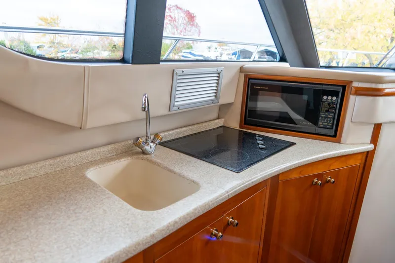 Slide: The Image of 2000 Carver 450 Voyager Pilothouse kitchen with sink, stovetop, and microwave. - 49