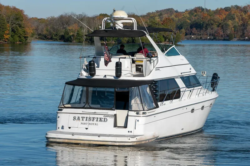 Slide: The Image of Carver 450 Voyager Pilothouse yacht cruising on a serene lake, autumn trees in background. - 5