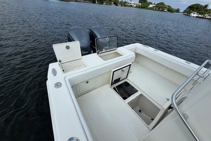 Slide: The Image of 2013 SeaVee 320B boat with open storage compartments and twin engines on a calm waterway. - 28