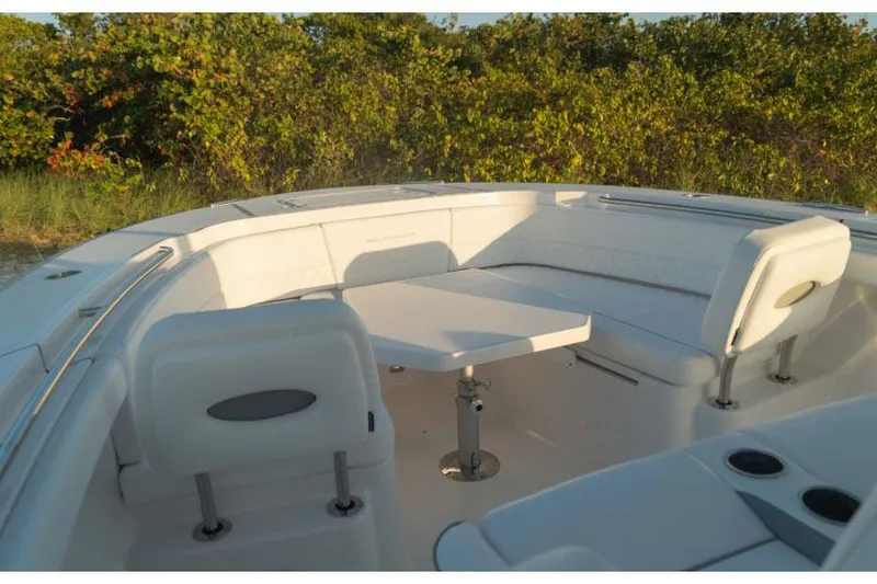 Slide: The Image of Manufacturer Provided Image: 2025 Southport 33 FE boat interior with white seating and table, surrounded by greenery. - 2
