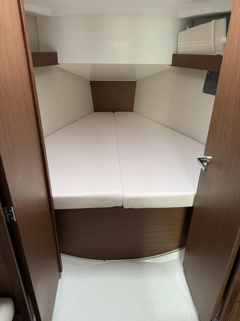 Slide: The Image of 2024 Beneteau Oceanis 34.1 cabin interior with cozy bed and wooden finish. - 6