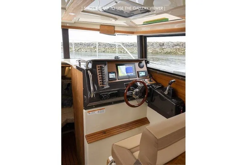 Slide: The Image of 2023 Ranger Tugs R-27 helm with navigation equipment and steering wheel, interior view. - 16