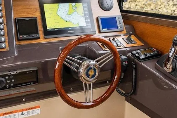 Slide: The Image of 2023 Ranger Tugs R-27 helm with navigation screens and wooden steering wheel. - 17