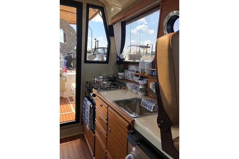 Slide: The Image of 2023 Ranger Tugs R-27 interior kitchen with stove, sink, and wooden cabinetry. - 18