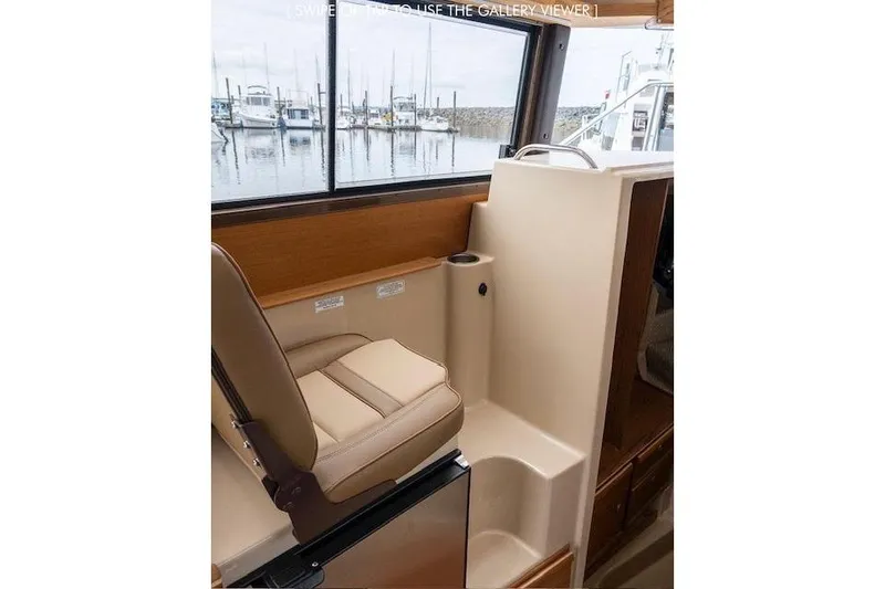 Slide: The Image of 2023 Ranger Tugs R-27 interior with seating and window view of marina. - 21