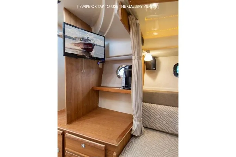 Slide: The Image of 2023 Ranger Tugs R-27 interior with TV, wooden cabinetry, and cozy seating area. - 29