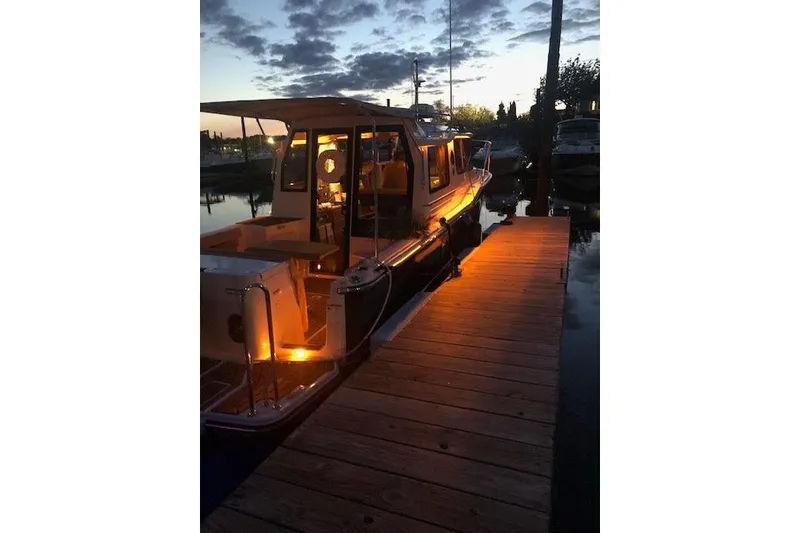 Slide: The Image of 2023 Ranger Tugs R-27 docked at sunset with warm interior lighting. - 6