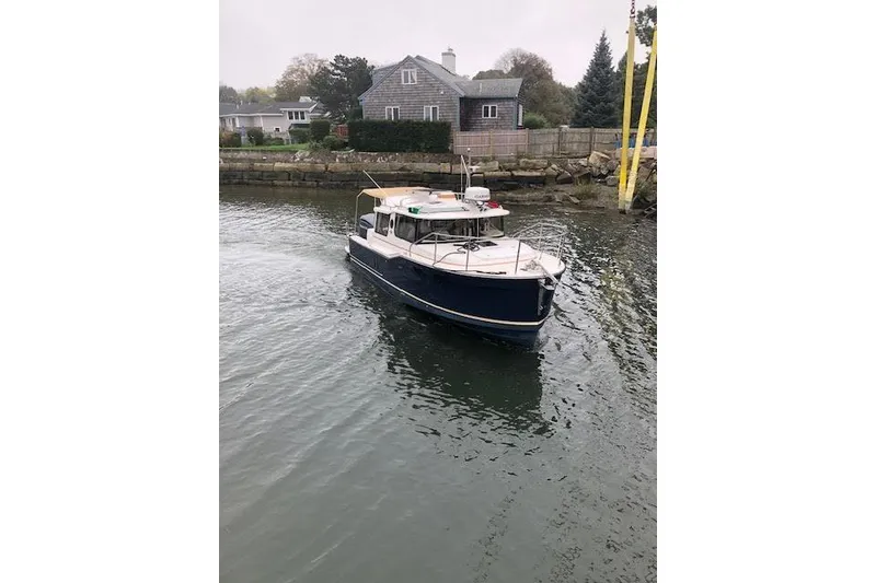 Slide: The Image of 2023 Ranger Tugs R-27 boat navigating near a waterfront home. - 8