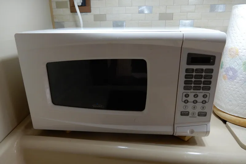 Slide: The Image of White microwave oven on kitchen counter with digital keypad and paper towel roll nearby. - 31