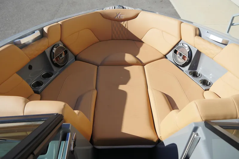 Slide: The Image of 2022 MasterCraft XT23 boat interior with tan seating and built-in speakers. - 11