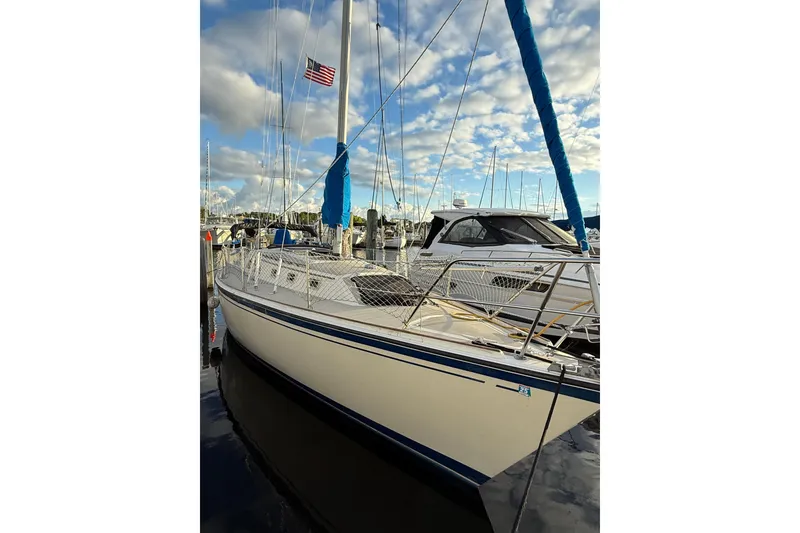 Slide: The Image of 1983 O'Day 34 sailboat docked, featuring blue accents and an American flag. - 1