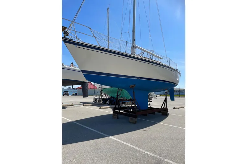 Slide: The Image of 1983 O'Day 34 sailboat on dry dock, blue and white hull, sunny day. - 13