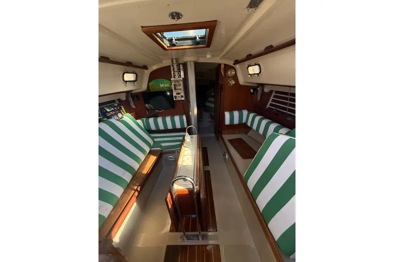 Slide: The Image of Interior of a 1983 O'Day 34 sailboat with green-striped seating and wood accents. - 15