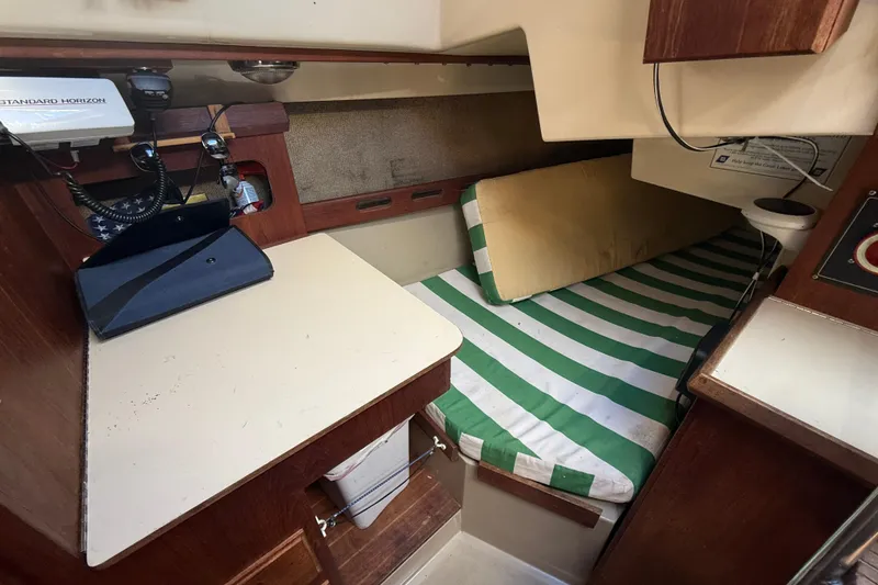 Slide: The Image of 1983 O'Day 34 sailboat interior with striped bedding and navigation equipment. - 16