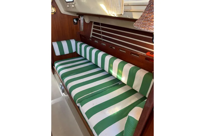 Slide: The Image of Green and white striped seating inside a 1983 O'Day 34 sailboat cabin. - 24