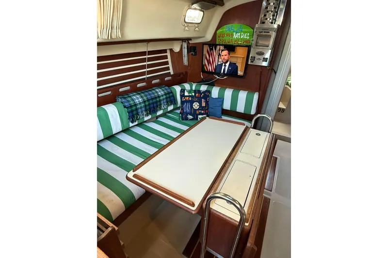 Slide: The Image of Interior of a 1983 O'Day 34 sailboat with striped seating and a mounted TV. - 31