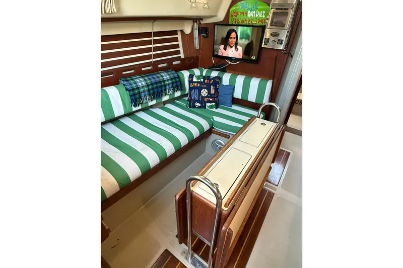Slide: The Image of Interior of 1983 O'Day 34 sailboat with striped seating, TV, and nautical decor. - 32