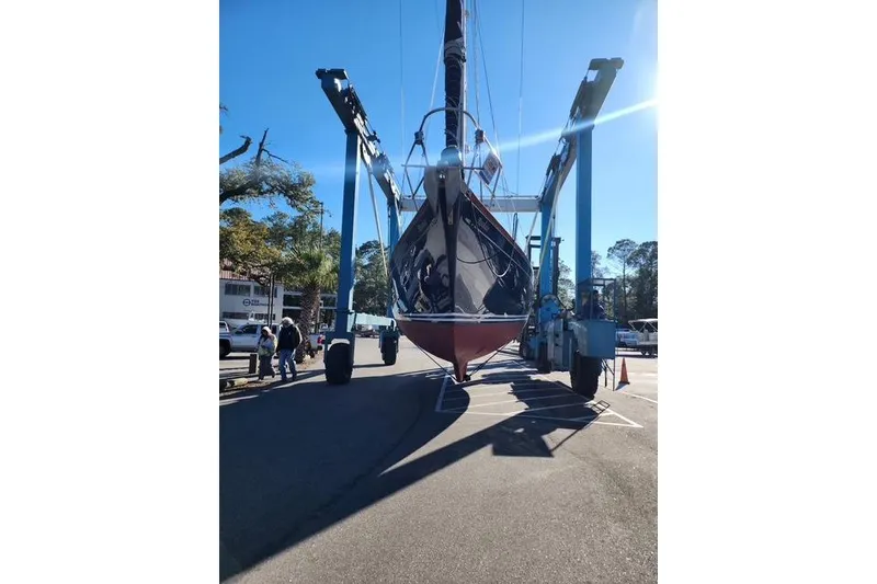 Slide: The Image of 1984 Bristol 45.5 Center Cockpit sailboat being lifted by a crane in a sunny marina. - 12