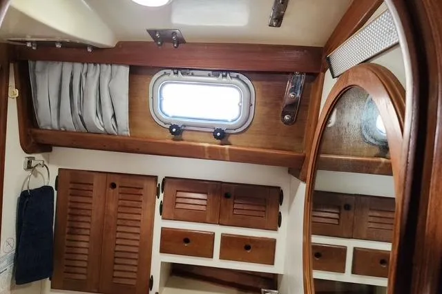 Slide: The Image of 1984 Bristol 45.5 Center Cockpit interior with wooden cabinets and porthole window. - 28