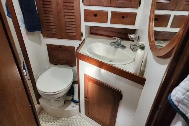 Slide: The Image of 1984 Bristol 45.5 Center Cockpit bathroom with wooden cabinets and white fixtures. - 30