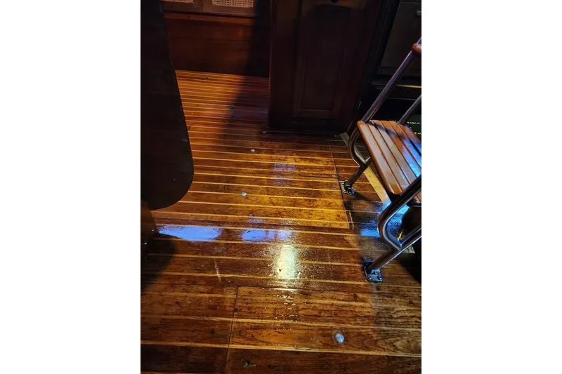 Slide: The Image of Polished wooden floor inside 1984 Bristol 45.5 Center Cockpit yacht, featuring a metal-framed chair. - 32