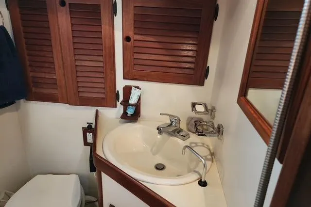 Slide: The Image of 1984 Bristol 45.5 Center Cockpit bathroom with wooden cabinets and sink. - 33