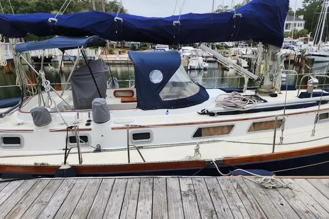 Slide: The Image of 1984 Bristol 45.5 Center Cockpit sailboat docked at a marina, featuring blue canvas covers. - 5