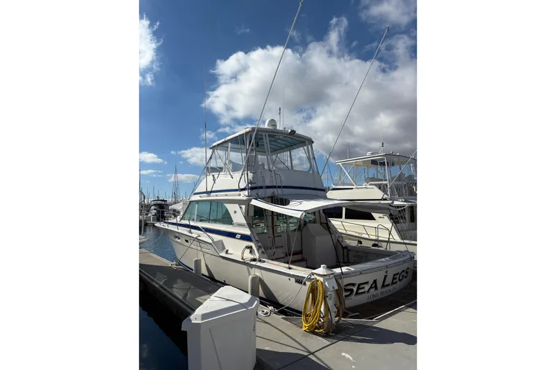 The Image of 1987 Bertram 46.6 yacht docked under a partly cloudy sky. - 0