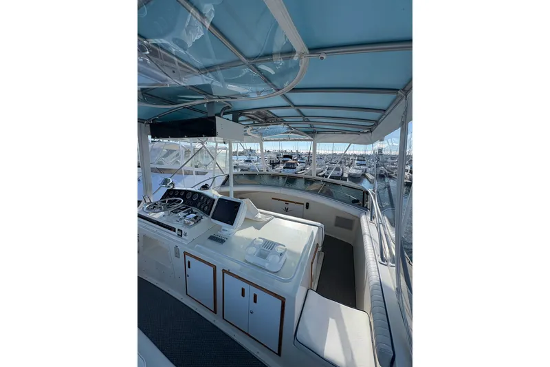 Slide: The Image of 1987 Bertram 46.6 yacht cockpit with helm, marina view, and blue canopy. - 19