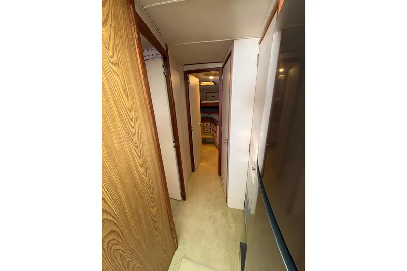 Slide: The Image of Narrow hallway inside 1987 Bertram 46.6 yacht, featuring wood paneling and carpeted floor. - 30