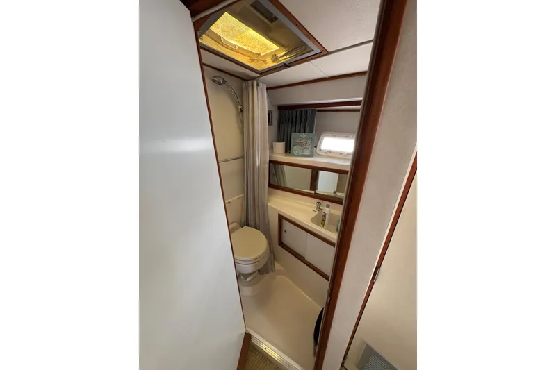 Slide: The Image of 1987 Bertram 46.6 yacht bathroom with shower, toilet, and sink, featuring wood accents. - 39