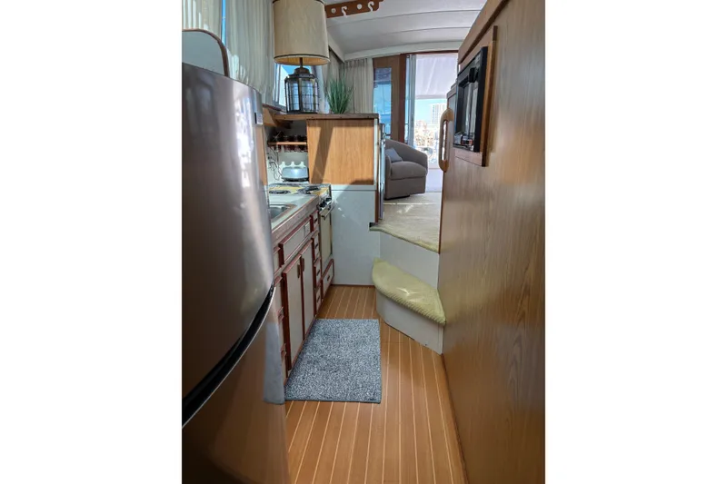 Slide: The Image of Interior of 1987 Bertram 46.6 yacht, featuring a compact kitchen and cozy living area. - 42