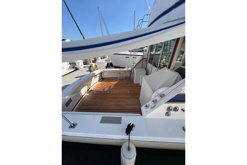 Slide: The Image of 1987 Bertram 46.6 yacht with spacious wooden deck and marina view. - 7