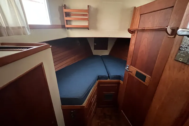 Slide: The Image of 1980 Grand Banks 42 Classic cabin with wooden interior and blue cushions. - 11