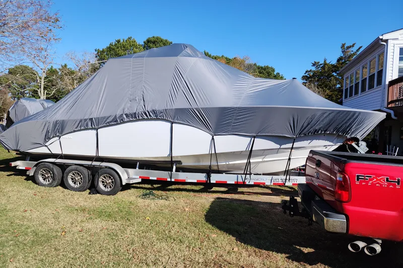 Slide: The Image of 2021 Cape Horn 32 XS boat covered on trailer, hitched to red truck. - 11