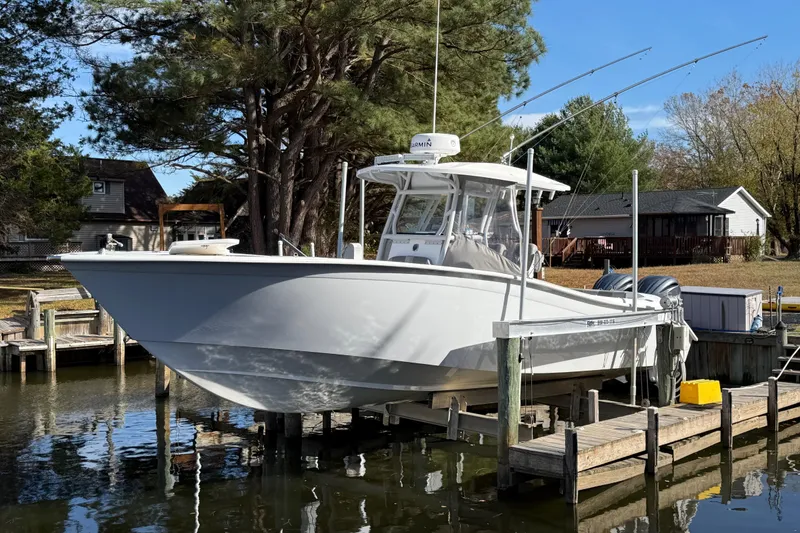 Slide: The Image of 2021 Cape Horn 32 XS boat docked by a lakeside, surrounded by trees and houses. - 2