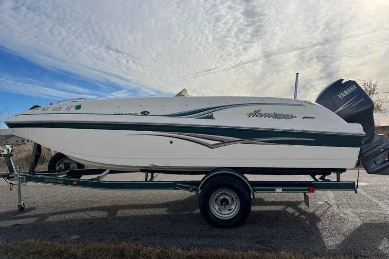 Slide: The Image of 2006 Hurricane FunDeck GS 194 OB boat on trailer, side view, under cloudy sky. - 3