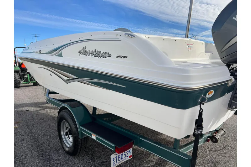 Slide: The Image of 2006 Hurricane FunDeck GS 194 OB boat on trailer, white and green design, clear sky background. - 6
