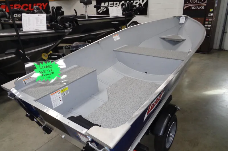 Slide: The Image of 2026 Lund WC-12 boat displayed in showroom, featuring spacious interior and durable design. - 2