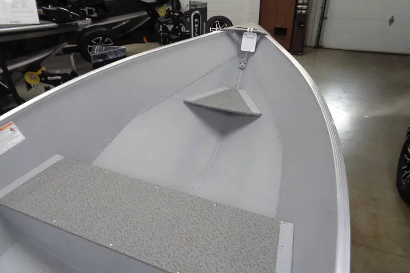 Slide: The Image of 2026 Lund WC-12 boat interior with gray seating and storage, displayed indoors. - 6