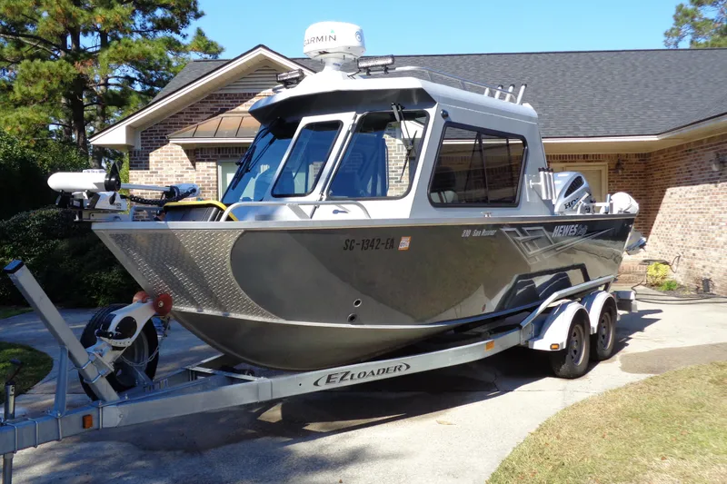 The Image of 2022 Hewes 210 Searunner ET Hardtop boat on trailer in driveway. - 0