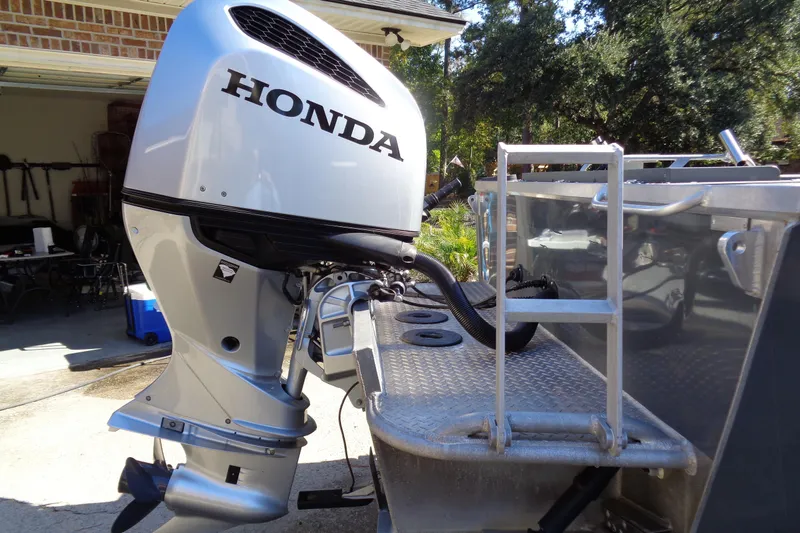 Slide: The Image of 2022 Hewes 210 Searunner ET Hartop with Honda outboard motor in a driveway setting. - 5